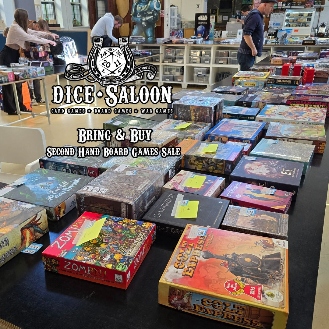 Second-hand board games for sale at Dice Saloon with various game boxes on a table.