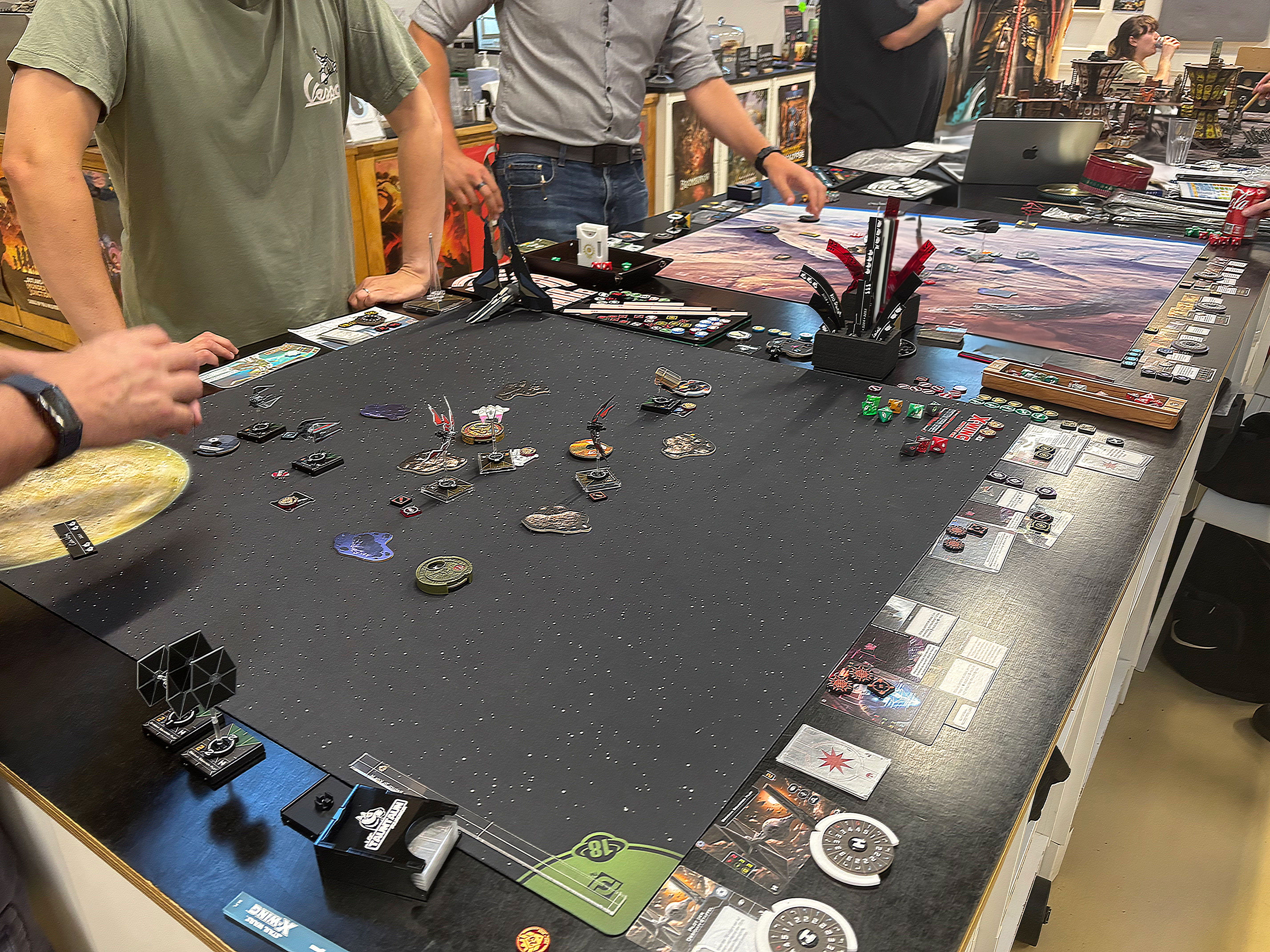 Two people playing a war game with various pieces and cards on a table.