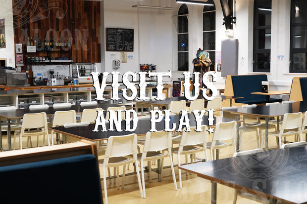 Indoor setting with tables, chairs, and a sign inviting people to visit and play.